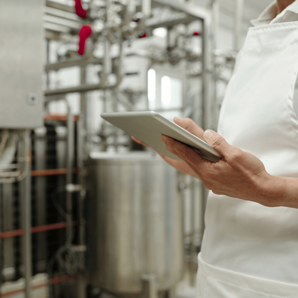 A person looking at an electronic device in an industrial plant
