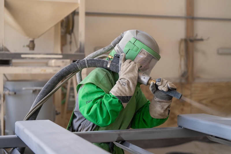 A man in a protective suit doing commercial blasting