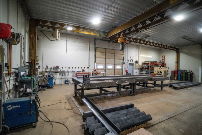 A room with garage doors, a high ceiling, and industrial equipment inside