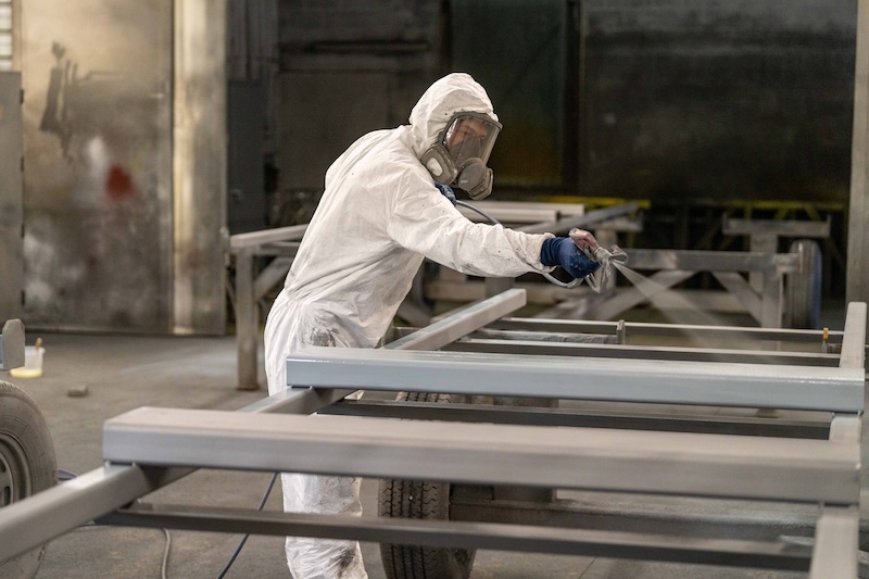 A man in a protective suit painting an industrial metal project